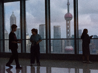 Several people are taking a look at the Huangpu River in a cafe as dark clouds are seen above the Huangpu River in Shanghai, China, on July...