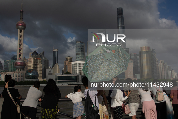 Several people are taking a look at the Huangpu River in a cafe as dark clouds are seen above the Huangpu River in Shanghai, China, on July...