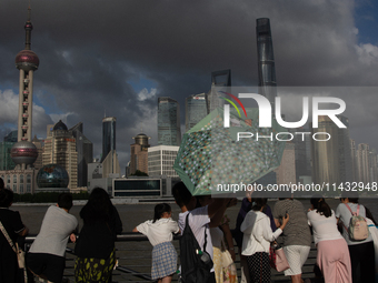 Several people are taking a look at the Huangpu River in a cafe as dark clouds are seen above the Huangpu River in Shanghai, China, on July...