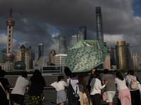 Several people are taking a look at the Huangpu River in a cafe as dark clouds are seen above the Huangpu River in Shanghai, China, on July...