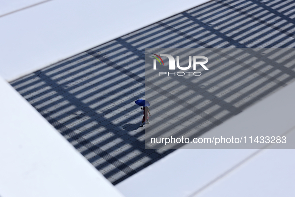 A woman is using an umbrella to protect herself from the sun in Singapore, on July 25, 2024. 