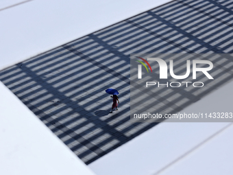 A woman is using an umbrella to protect herself from the sun in Singapore, on July 25, 2024. (