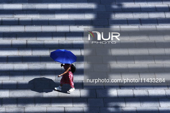 A woman is using an umbrella to protect herself from the sun in Singapore, on July 25, 2024. 