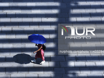 A woman is using an umbrella to protect herself from the sun in Singapore, on July 25, 2024. (