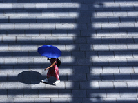 A woman is using an umbrella to protect herself from the sun in Singapore, on July 25, 2024. (