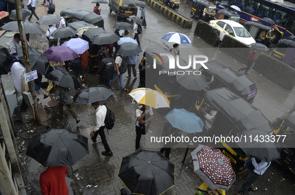 People are carrying umbrellas while going to their workplace during rainfall in Mumbai, India, on July 25, 2024. 