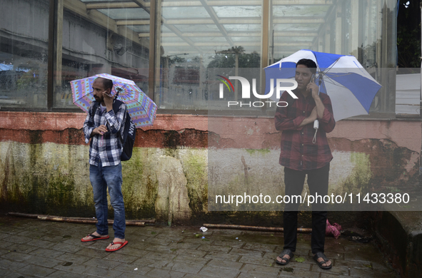 Men are talking on their phones during rainfall in Mumbai, India, on July 25, 2024. 