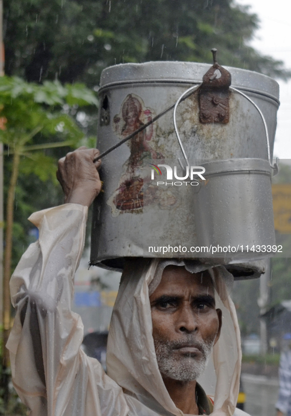 A man is carrying a tin container on his head during rainfall in Mumbai, India, on July 25, 2024. 