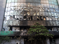 A cyclist is crossing past the burnt building of the Bangladesh Bridge Authority, which students are setting on fire amid the ongoing anti-q...