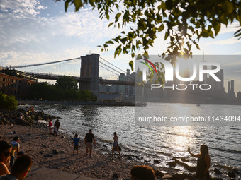  A view on Pebble Beach, Brooklyn Bridge and Manhattan skyline during sunset over the East River in New York City, United States of America...