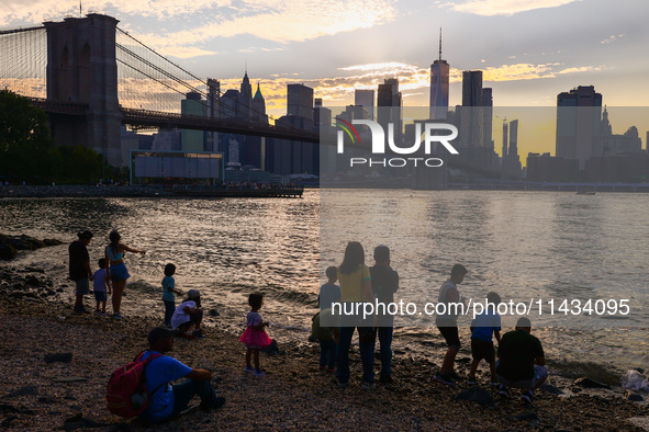  A view on Pebble Beach, Brooklyn Bridge and Manhattan skyline during sunset over the East River in New York City, United States of America...