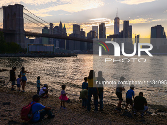  A view on Pebble Beach, Brooklyn Bridge and Manhattan skyline during sunset over the East River in New York City, United States of America...