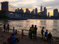  A view on Pebble Beach, Brooklyn Bridge and Manhattan skyline during sunset over the East River in New York City, United States of America...