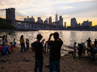  A view on Pebble Beach, Brooklyn Bridge and Manhattan skyline during sunset over the East River in New York City, United States of America...