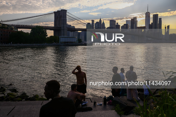  A view on Pebble Beach, Brooklyn Bridge and Manhattan skyline during sunset over the East River in New York City, United States of America...