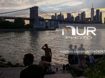  A view on Pebble Beach, Brooklyn Bridge and Manhattan skyline during sunset over the East River in New York City, United States of America...