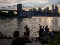  A view on Pebble Beach, Brooklyn Bridge and Manhattan skyline during sunset over the East River in New York City, United States of America...