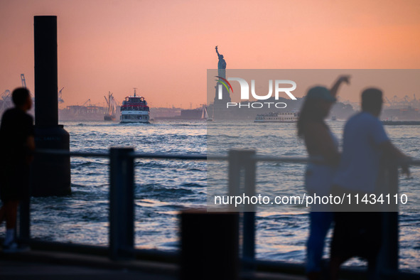  Sunset over the East River and a view on the Statue of Liberty in New York City, United States of America on July 7th, 2024.  