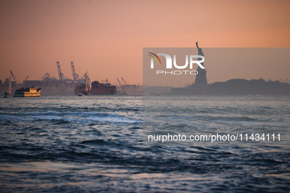  Sunset over the East River and a view on the Statue of Liberty in New York City, United States of America on July 7th, 2024.  