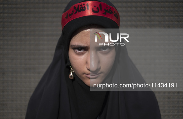 A young veiled Iranian schoolgirl is wearing a religious headband with Persian script that reads, ''Daughters of the Revolution,'' while par...