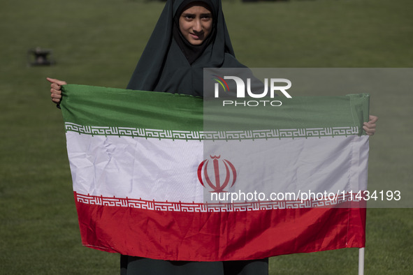 A young veiled schoolgirl is holding an Iranian flag while participating in a gathering to support the mandatory hijab at the Azadi (Freedom...