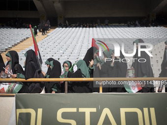 Young veiled schoolgirls are arriving to participate in a gathering to support mandatory hijab at the Azadi (Freedom) Stadium in western Teh...