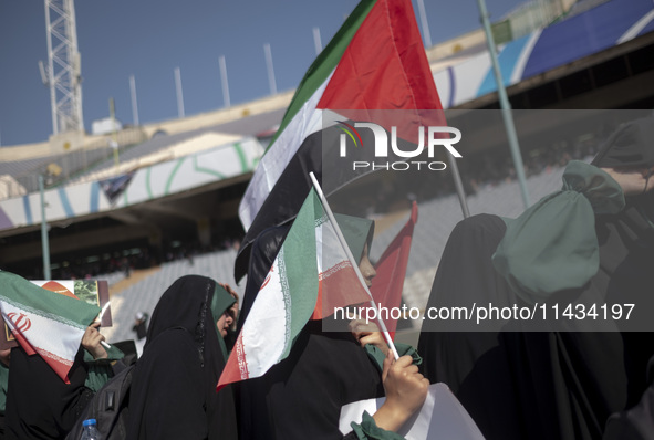 Young veiled schoolgirls are carrying an Iranian flag and a Palestinian flag while arriving to participate in a gathering to support mandato...