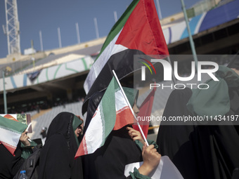 Young veiled schoolgirls are carrying an Iranian flag and a Palestinian flag while arriving to participate in a gathering to support mandato...