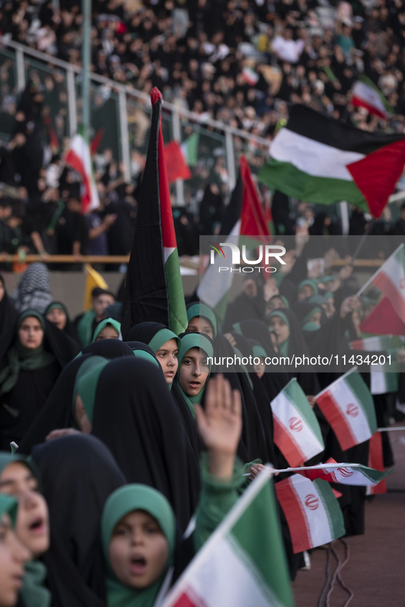 Veiled schoolgirls are holding Iranian flags and Palestinian flags while participating in a gathering to support the mandatory hijab at the...