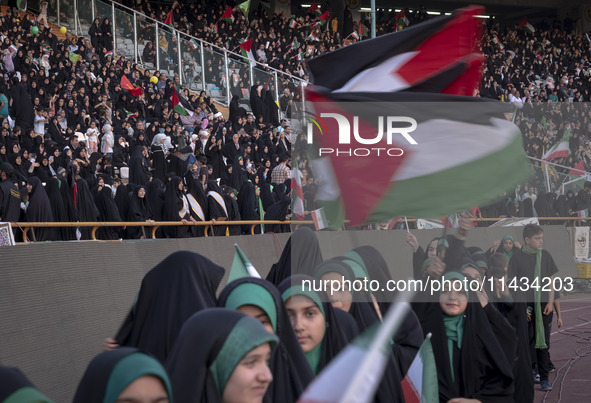 Young veiled Iranian schoolgirls are waving Palestinian flags while participating in a gathering to support the mandatory hijab at the Azadi...