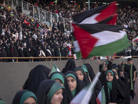 Young veiled Iranian schoolgirls are waving Palestinian flags while participating in a gathering to support the mandatory hijab at the Azadi...