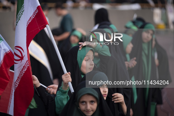 A young veiled schoolgirl is holding an Iranian flag while participating in a gathering to support the mandatory hijab at the Azadi (Freedom...