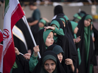 A young veiled schoolgirl is holding an Iranian flag while participating in a gathering to support the mandatory hijab at the Azadi (Freedom...