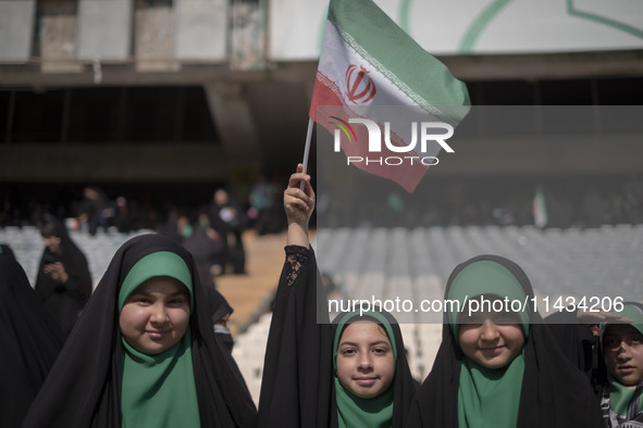 A young veiled schoolgirl is waving an Iranian flag while participating in a gathering to support mandatory hijab at the Azadi (Freedom) Sta...