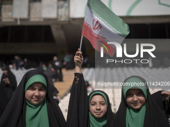 A young veiled schoolgirl is waving an Iranian flag while participating in a gathering to support mandatory hijab at the Azadi (Freedom) Sta...