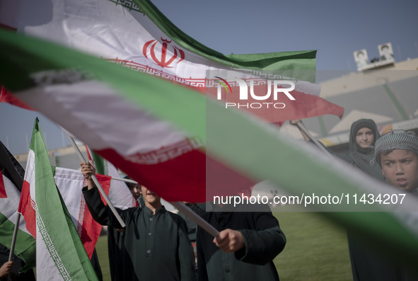 Young schoolboys are waving Iranian flags while participating in a gathering to support mandatory hijab at the Azadi (Freedom) Stadium in we...