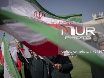 Young schoolboys are waving Iranian flags while participating in a gathering to support mandatory hijab at the Azadi (Freedom) Stadium in we...