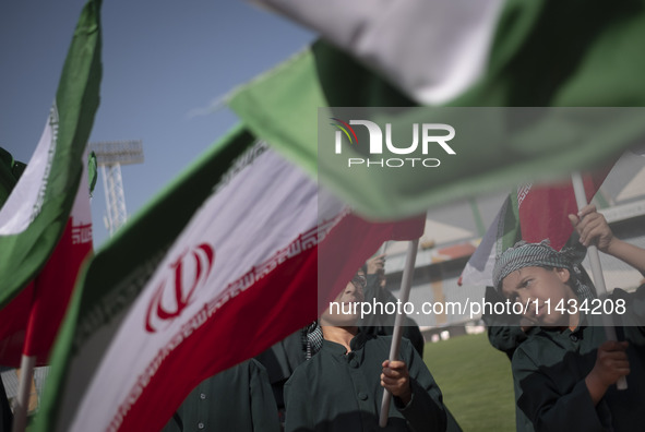 Young schoolboys are waving Iranian flags while participating in a gathering to support mandatory hijab at the Azadi (Freedom) Stadium in we...