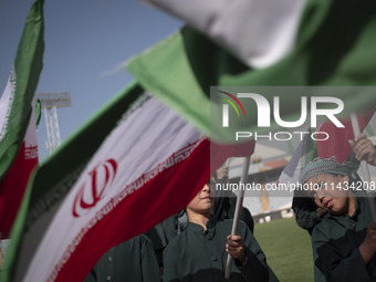 Young schoolboys are waving Iranian flags while participating in a gathering to support mandatory hijab at the Azadi (Freedom) Stadium in we...