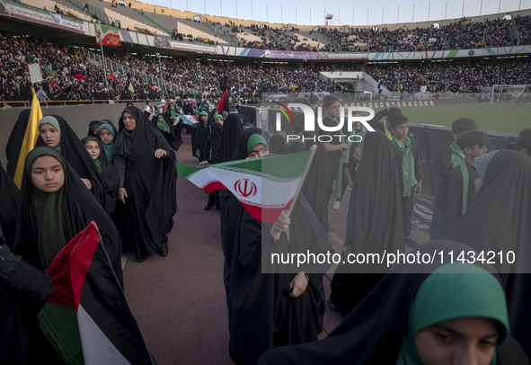 A young veiled schoolgirl is waving an Iranian flag while participating in a gathering to support mandatory hijab at the Azadi (Freedom) Sta...