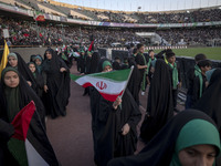 A young veiled schoolgirl is waving an Iranian flag while participating in a gathering to support mandatory hijab at the Azadi (Freedom) Sta...