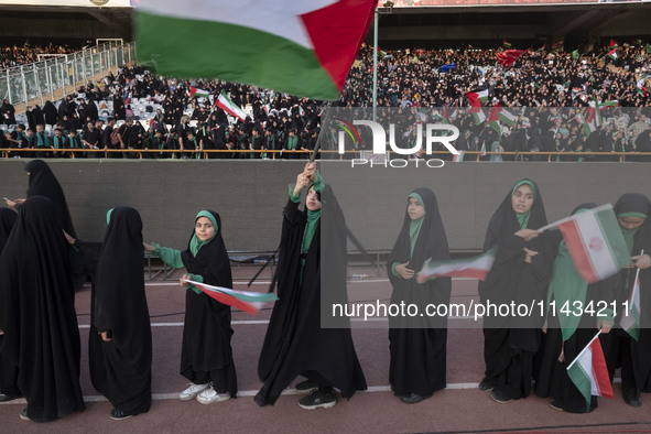 Young veiled schoolgirls are carrying Iranian flags as one of them is waving a Palestinian flag while participating in a gathering to suppor...