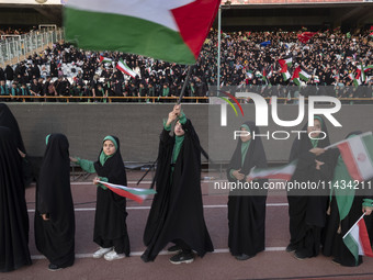 Young veiled schoolgirls are carrying Iranian flags as one of them is waving a Palestinian flag while participating in a gathering to suppor...