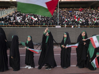 Young veiled schoolgirls are carrying Iranian flags as one of them is waving a Palestinian flag while participating in a gathering to suppor...