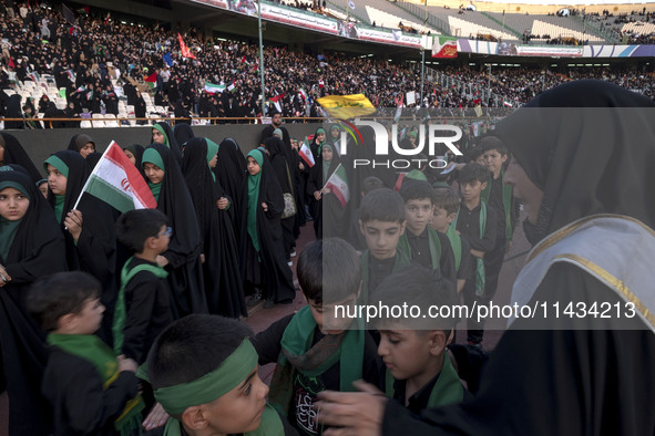 A veiled woman is helping Iranian schoolboys stand in a military formation during a gathering to support the mandatory hijab at the Azadi (F...