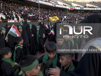 A veiled woman is helping Iranian schoolboys stand in a military formation during a gathering to support the mandatory hijab at the Azadi (F...