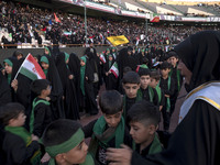 A veiled woman is helping Iranian schoolboys stand in a military formation during a gathering to support the mandatory hijab at the Azadi (F...