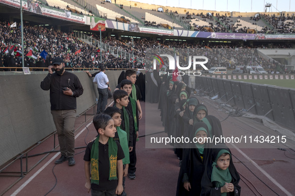 Young veiled Iranian schoolgirls and schoolboys are standing in military formation, while participating in a gathering to support mandatory...