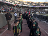 Young veiled Iranian schoolgirls and schoolboys are standing in military formation, while participating in a gathering to support mandatory...