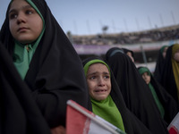 A young veiled Iranian schoolgirl is crying as a reaction to a religious song while participating in a gathering to support mandatory hijab...